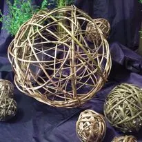 Woven willow spheres and decorative basketry pieces on a cloth backdrop