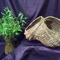 Willow basketry display with greenery and woven pieces on a dark backdrop
