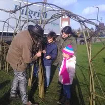 Group building a living willow structure outdoors during a workshop
